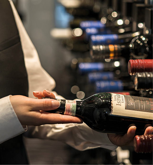 A bartender carefully pulling a bottle of red wine out from the rack