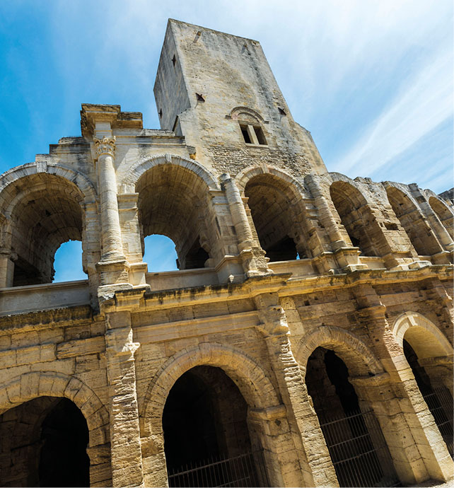 Upwards shot of the archways of a stone building in Arles, France