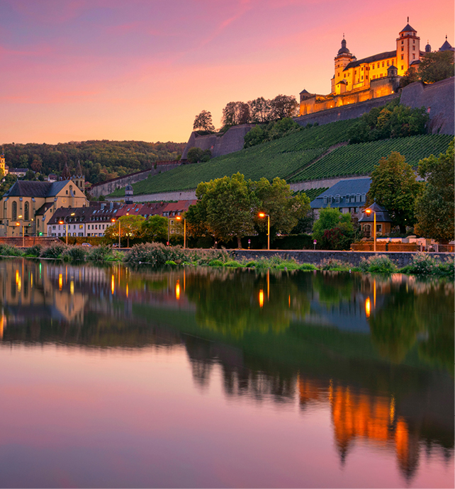 Castle on top of a hill overlooking the banks of the Main river under a vibrant pink, orange and purple sunset