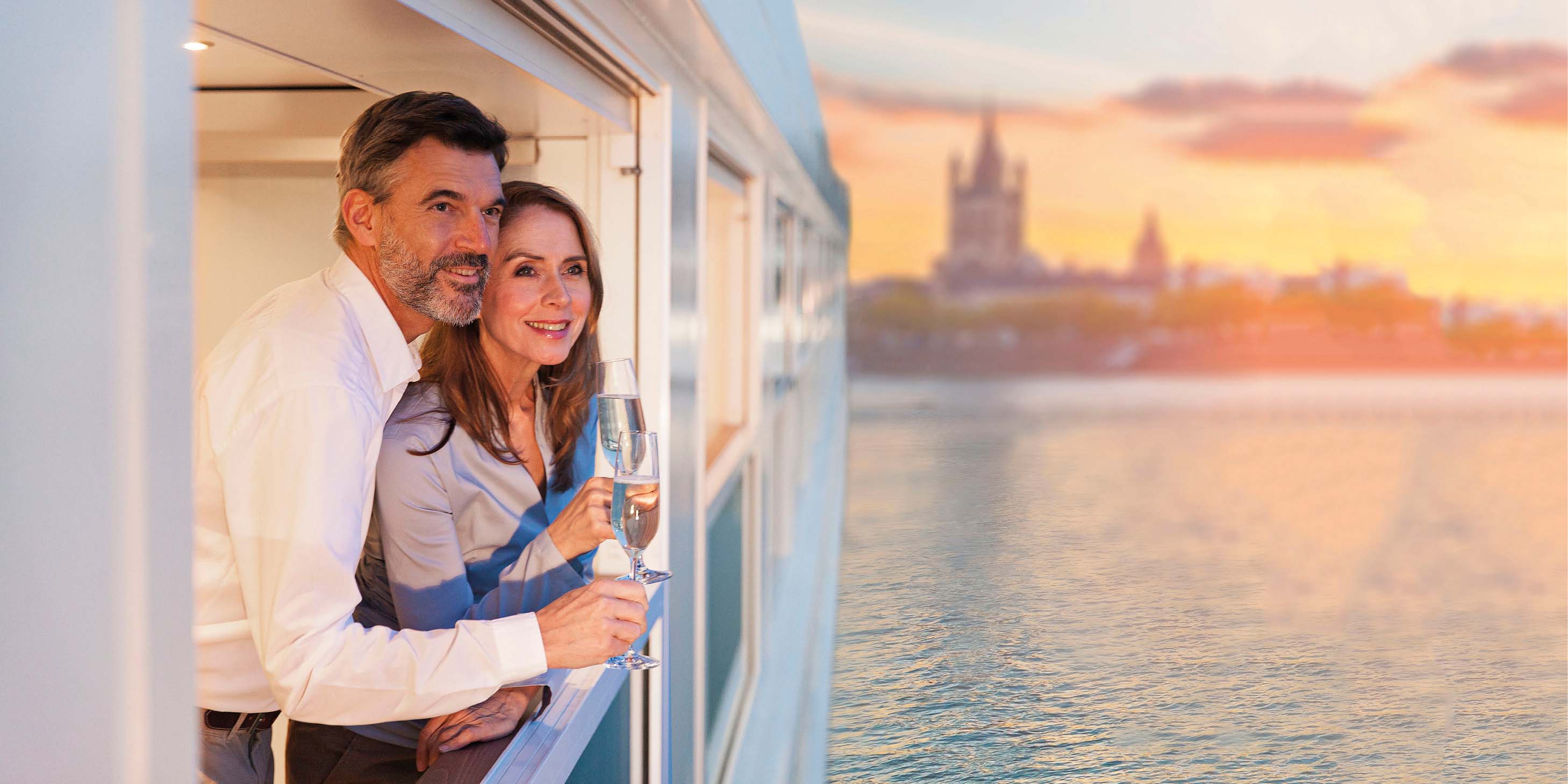 Couple enjoying a glass of Champagne whilst admiring the view on board a luxury river ship  