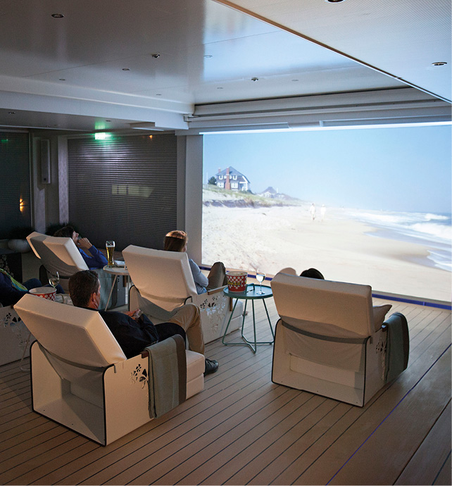 Innovate cinema space with lounge seating and guests enjoying a sunny beach scene 
