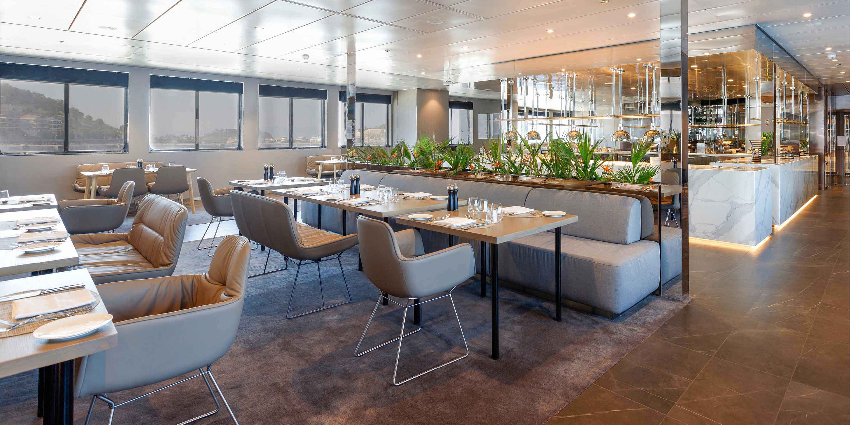 Spacious and stylish restaurant, with modern seating and tables prepared for service, and a bar in the background