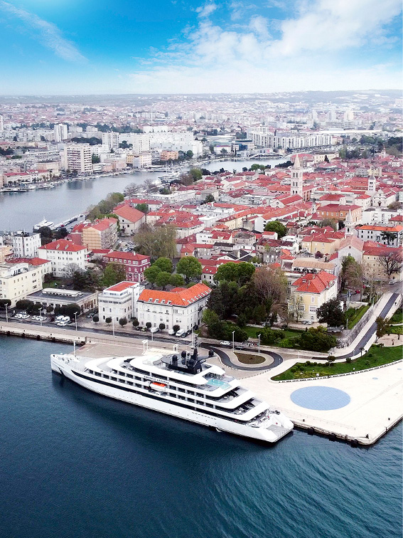 A luxury yacht is docked in a harbour close to a Croatian town
