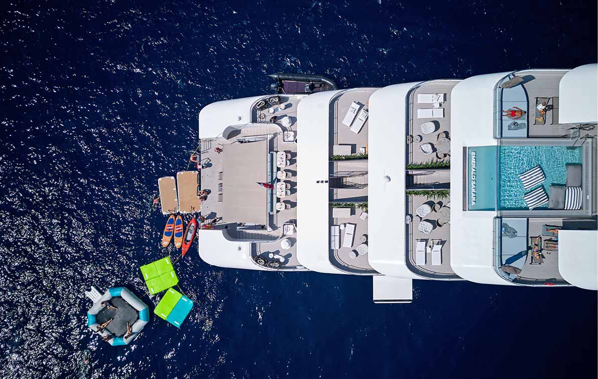 Luxury yacht on the sun-dazzling waters, as a kayaker paddles nearby, with the coastline in the distance