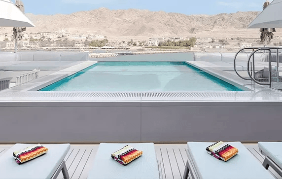 Luxurious lounge chairs overlooking infinity-style pool on board a luxury yacht cruise 