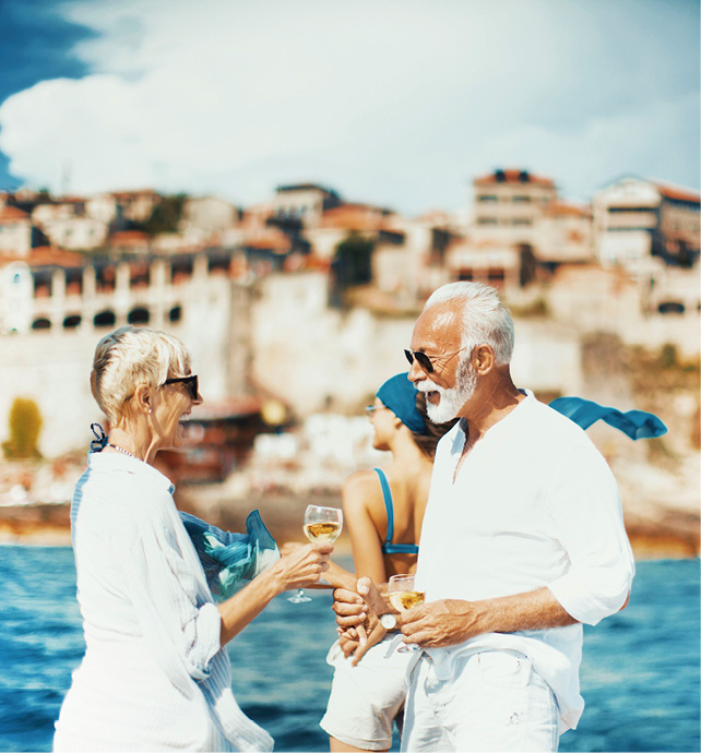 A couple dressed in white enjoying a glass of white wine overlooking the sea and coast of the Mediterranean